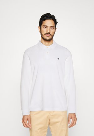 Hvit langermet polo skjorte med krage og tre knappelukkinger, med en liten brodert logo på venstre bryst.