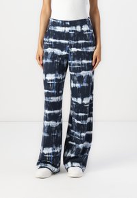Wijde pijpen broek in marineblauw met een tie-dye patroon van blauwe en witte strepen. Gemaakt van een lichtgewicht stof met een zachte textuur.