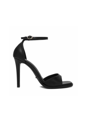 Sandalo con tacco alto in pelle nera, con cinturino alla caviglia e fibbia, punta aperta e sottile tacco a stiletto su sfondo bianco.