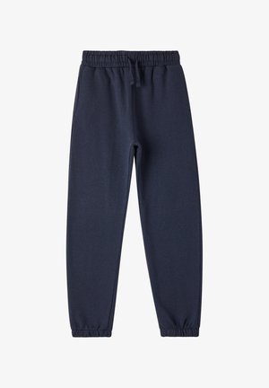 Biała koszula z długim rękawem, granatowe spodnie dresowe, czarne sneakersy z białymi akcentami. Prosty design, miękka tekstura, luźny krój.