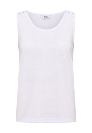 Femme portant un haut blanc sans manches et un pantalon vert, vue de dos sur un fond clair uni.