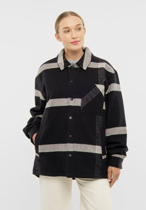 Svart och grårandig jacka med mjuk textur, knappstängning och långa ärmar. Har en bröstficka och en stor krage.