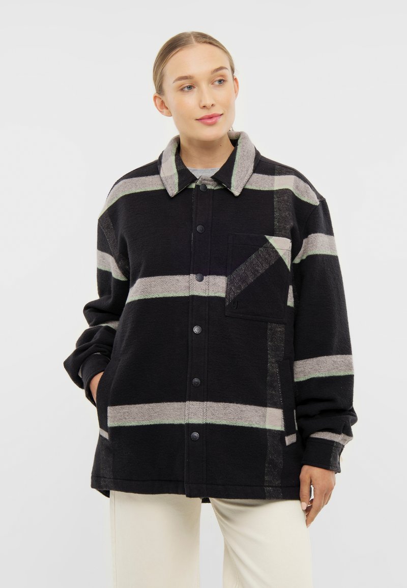 Černá a šedá pruhovaná bunda s měkkou texturou, zapínání na knoflíky a dlouhými rukávy. Obsahuje náprsní kapsu a velký límec.