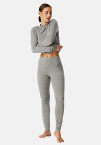 Grijze lange mouw top en aansluitende leggings gemaakt van zachte, rekbare materialen. Het ontwerp heeft een ronde halslijn en taps toelopende benen.
