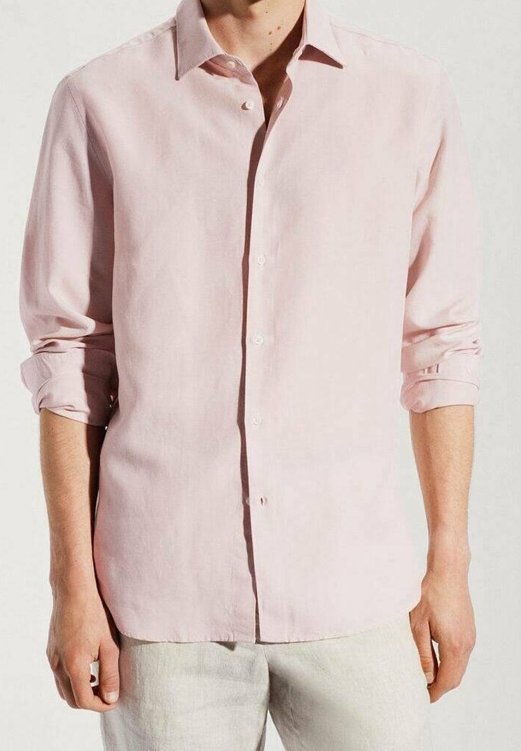 Camisa de lino rosa claro con cuello abotonado, mangas largas remangadas, corte recto y textura suave. Botones blancos acentúan la parte delantera.