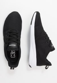 Zwarte mesh sportchoenen met een ronde neus, vetersluiting, witte rubberen zool en logo-detail op de tong en hiel.