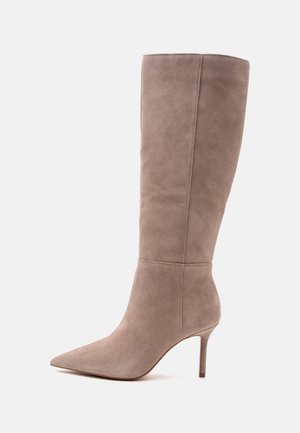 Botte mi-haute en daim taupe avec bout pointu et talon haut fin sur fond clair uni.
