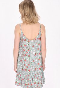 Abito floreale azzurro chiaro con spalline sottili, caratterizzato da una stampa di fragole e fiori, con un orlo a balze svasato sul fondo.