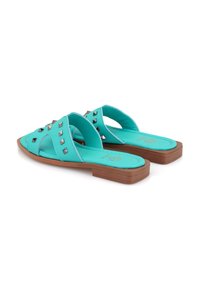 Aqua instap sandalen met een platte bruine zool, met zilveren studs op de bovenkant. Zacht materiaal en een kruisband ontwerp voor extra comfort.