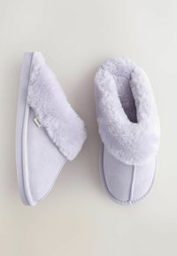 Pantofole lilla con morbido polsino in pelliccia sintetica, corpo in suede e forma arrotondata. La suola è piatta e presenta un'etichetta logo discreta.