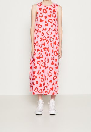 Vestido midi rosa sin mangas con estampado de corazones rojos dispersos, combinado con zapatillas blancas de caña alta, sobre un fondo claro y liso.