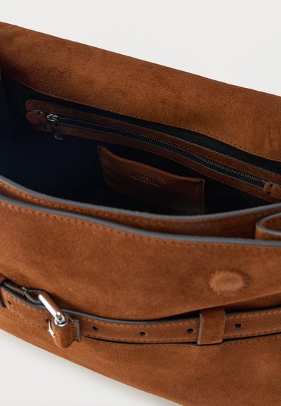 Καφέ τσάντα από σουέτ με μαύρο υφασμάτινο εσωτερικό, τσέπη με φερμουάρ και κλείσιμο με ζώνη και ασημένια αγκράφα.