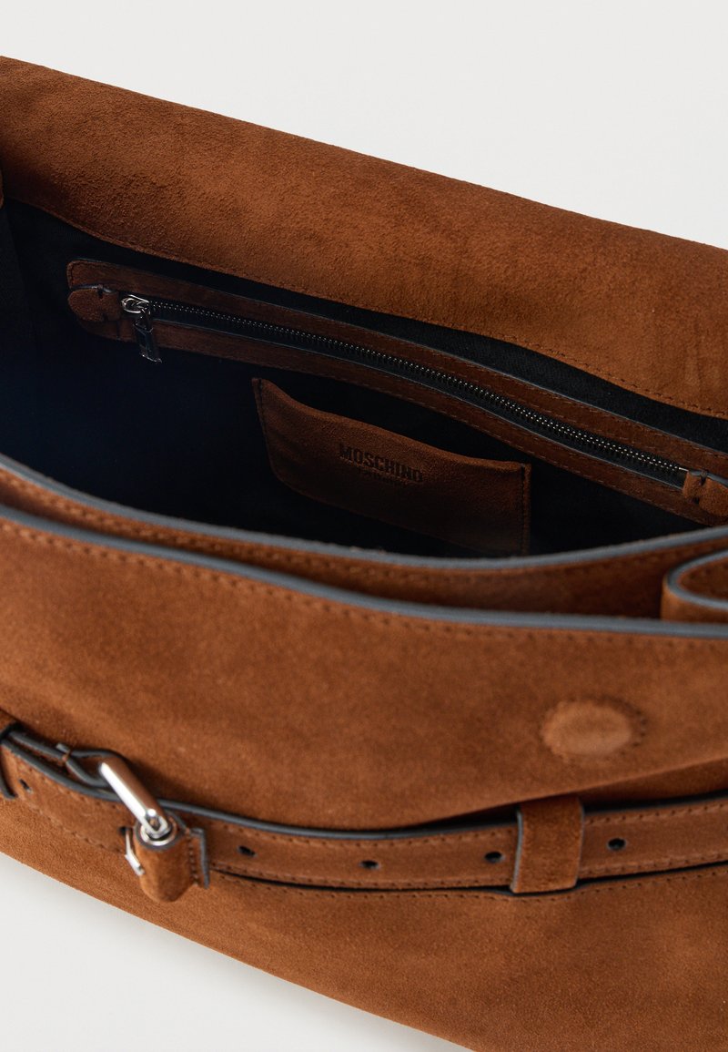 Sac à main en suède marron avec intérieur en tissu noir, poche zippée et fermeture style ceinture avec boucle argentée.