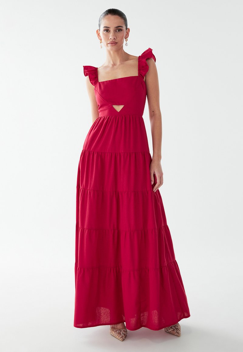 Robe maxi rouge avec un design à plusieurs niveaux, décolleté carré et bretelles à volants. Présente une découpe à la taille et une silhouette fluide.