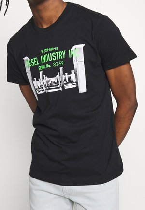 T-shirt en coton noir avec un imprimé graphique en blanc et vert, affichant "DIESEL INDUSTRY INC." avec un numéro de série et un design de pilier.