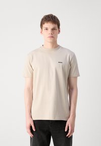 Lyse beige crew neck t-shirt lavet af blødt materiale, med korte ærmer og lille sort "BOSS" logo på venstre bryst.