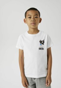 T-shirt en coton blanc avec un design de pirate en cartoon noir sur la poitrine, orné de détails colorés contrastants et à manches courtes.