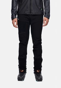 Zwarte buitenbroek met een taps toelopende pasvorm, voorzien van meerdere zakken, verstevigde knieën en een gladde textuur. Compatibel met skistiefels.