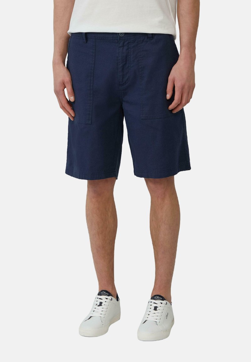 Donkerblauwe katoenen shorts met zakken, lichtgewicht stof, rechte pijp, gedragen met witte sneakers en een eenvoudige witte t-shirt.