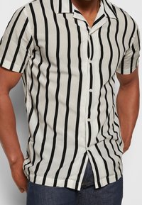 Korte mouwen overhemden met knopen van lichtgewicht stof, met smalle zwarte strepen op een witte achtergrond en een klassiek kraagontwerp.