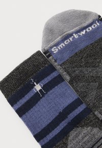 Calcetines de mezcla de lana con rayas en gris oscuro, azul marino y azul con un patrón, puntera gris y el logo "Smartwool" cerca del puño.