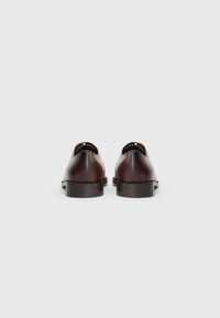 Scarpe in pelle marrone con finitura liscia, parte posteriore arrotondata e tacco nero basso e solido. Design semplice e minimalista senza decorazioni.