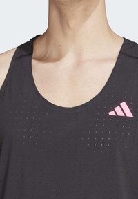 Czarny sportowy top na ramiączkach z perforowaną teksturą i różowym logo Adidas na lewej piersi. Bezrękawnik z okrągłym dekoltem.