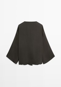 Top grigio scuro, dalla vestibilità ampia, con scollo rotondo e maniche larghe e lunghe. Tessuto liscio senza elementi metallici o motivi visibili. Orlo piatto.