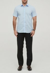 Chemise bleu clair à manches courtes avec un col boutonné, associée à un pantalon noir. La chemise présente une texture lisse et un éclat subtil.
