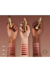 Tre mani tengono tubetti di rossetto, mostrando le tonalità applicate su braccia. I colori includono un marrone scuro, rosa nudo e rossi vivaci in diverse finiture.