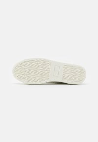 Sola di sneaker bianca con un motivo a zig zag testurizzato, caratterizzata da una superficie liscia e un'impronta rettangolare del logo vicino al tallone.