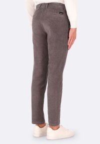 Pantaloni in corda grigia con righe verticali, design aderente, vita elastica e tasca posteriore. Abbinati a sneakers bianche.