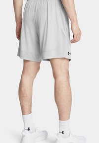 Shorts de sport gris clair en matériau respirant, dotés d'une taille élastique et d'un petit logo noir sur le côté.