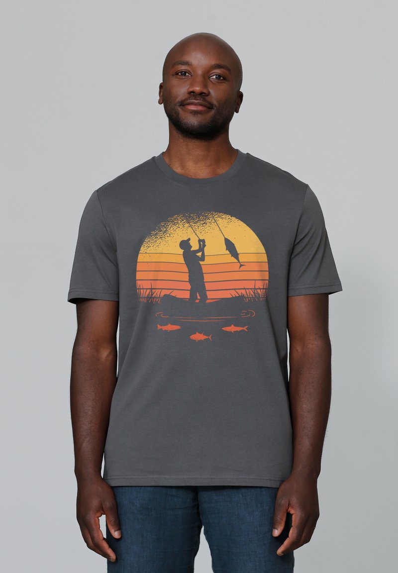 Grijze katoenen T-shirt met een oranje zonsondergangafbeelding van een visser met vissen, weergegeven in een rond ontwerp boven een lijn van kleinere vissen.