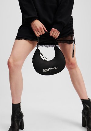 Czarna torba hobo o gładkiej fakturze i zaokrąglonym kształcie. Posiada zamek błyskawiczny oraz nadrukowane białe logo "KARL LAGERFELD JEANS".