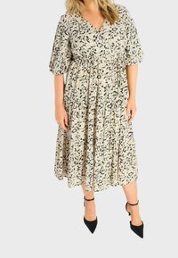 Šaty s květinovým vzorem a V výstřihem, krátkými nabíranými rukávy a vtaženým pasem; mají sukně do kolen v béžové a černé barvě, které krásně splývá.