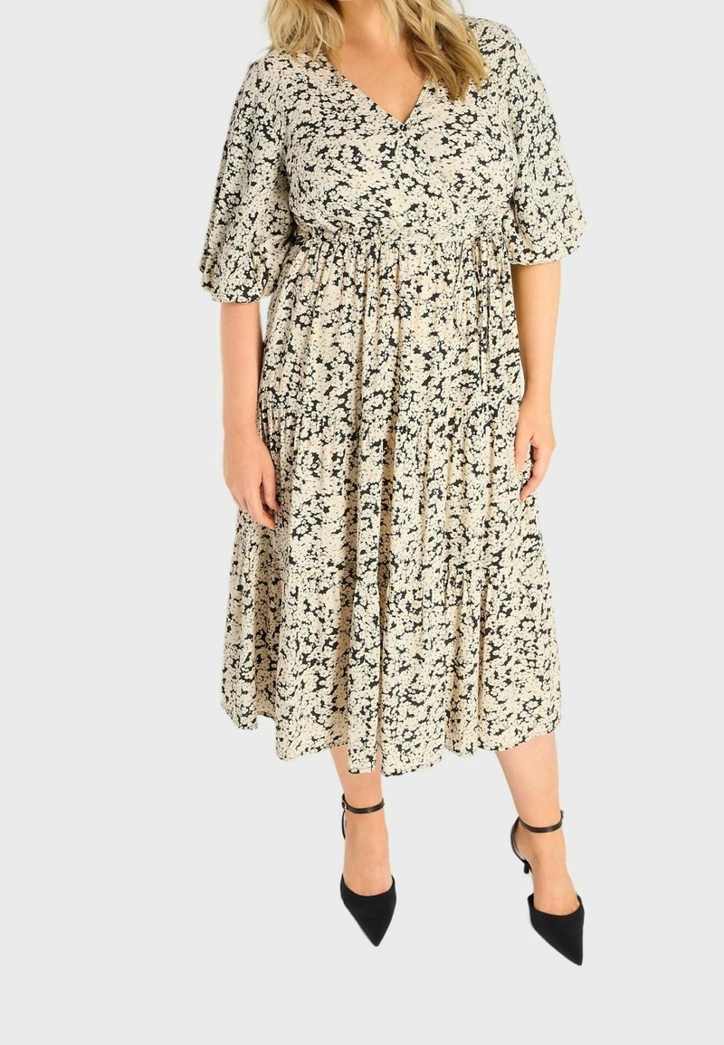 Šaty s květinovým vzorem a V výstřihem, krátkými nabíranými rukávy a vtaženým pasem; mají sukně do kolen v béžové a černé barvě, které krásně splývá.