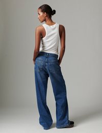 Μπλε τζιν παντελόνι με φαρδιά γραμμή και ψηλή μέση, με πίσω τσέπες. Συνδυάζεται με αμάνικο λευκό τοπ. Λείο ύφασμα, casual σχέδιο.