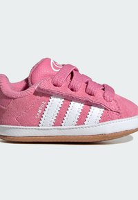 Růžové semišové tenisky mají bílý design se třemi pruhy, kulatou špičku a odpovídající tkaničky. Bílé gumové podrážky s gumovým vnějším podkresem.