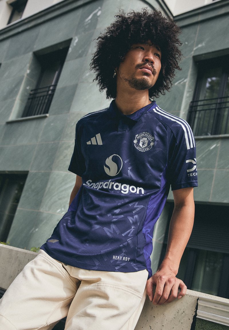 Tumši zils Manchester United krekls ar rakstainu tekstūru, baltām Adidas svītrām un "Snapdragon" logo. Vieglas, elpojošas audums.