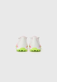 White athletic shoes with pink accents and a green textured sole. Designed with a streamlined shape and contrasting color panels.