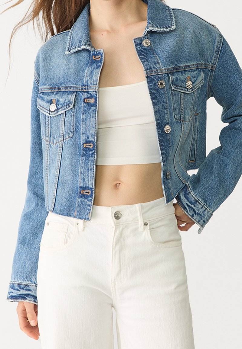Jeansjacka i ljusblått, med en klassisk design och två bröstfickor, silverdetaljer och trasig nederkant. Matchas med vita byxor.
