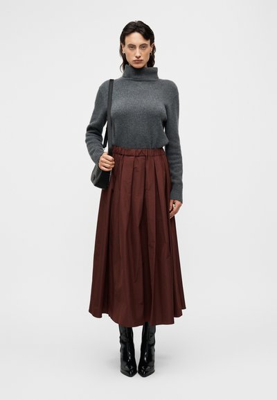 Γκρι πουλόβερ ζιβάγκο συνδυασμένο με μια ροή μπορντό μίντι φούστα, μαύρες μπότες με ψηλό τακούνι και μαύρη τσάντα ώμου. Ομαλή υφή σε όλη την επιφάνεια.