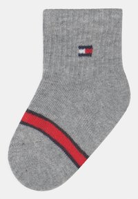 Calzino grigio alla caviglia con texture a coste, caratterizzato da una striscia rossa e blu all'orlo e un piccolo logo in blu, bianco e rosso.