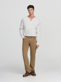 Maglietta henley a maniche lunghe grigio chiaro con tre bottoni, abbinata a pantaloni chinos color sabbia a gamba dritta e scarpe marroni con lacci. Vestibilità strutturata e trama visibile.