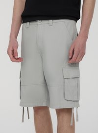 Pantaloni cargo grigi chiari realizzati in misto cotone, con numerose tasche laterali, passanti per cintura e coulisse regolabile all'orlo.
