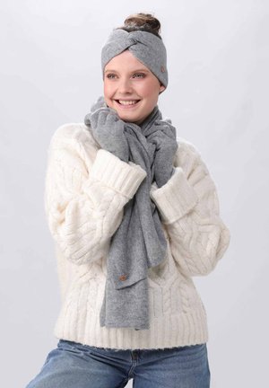 Grå stofhovedbånd med snoet design, parret med et matchende tørklæde. Begge accessories komplimenteres af en cremefarvet kabelstrikket sweater.
