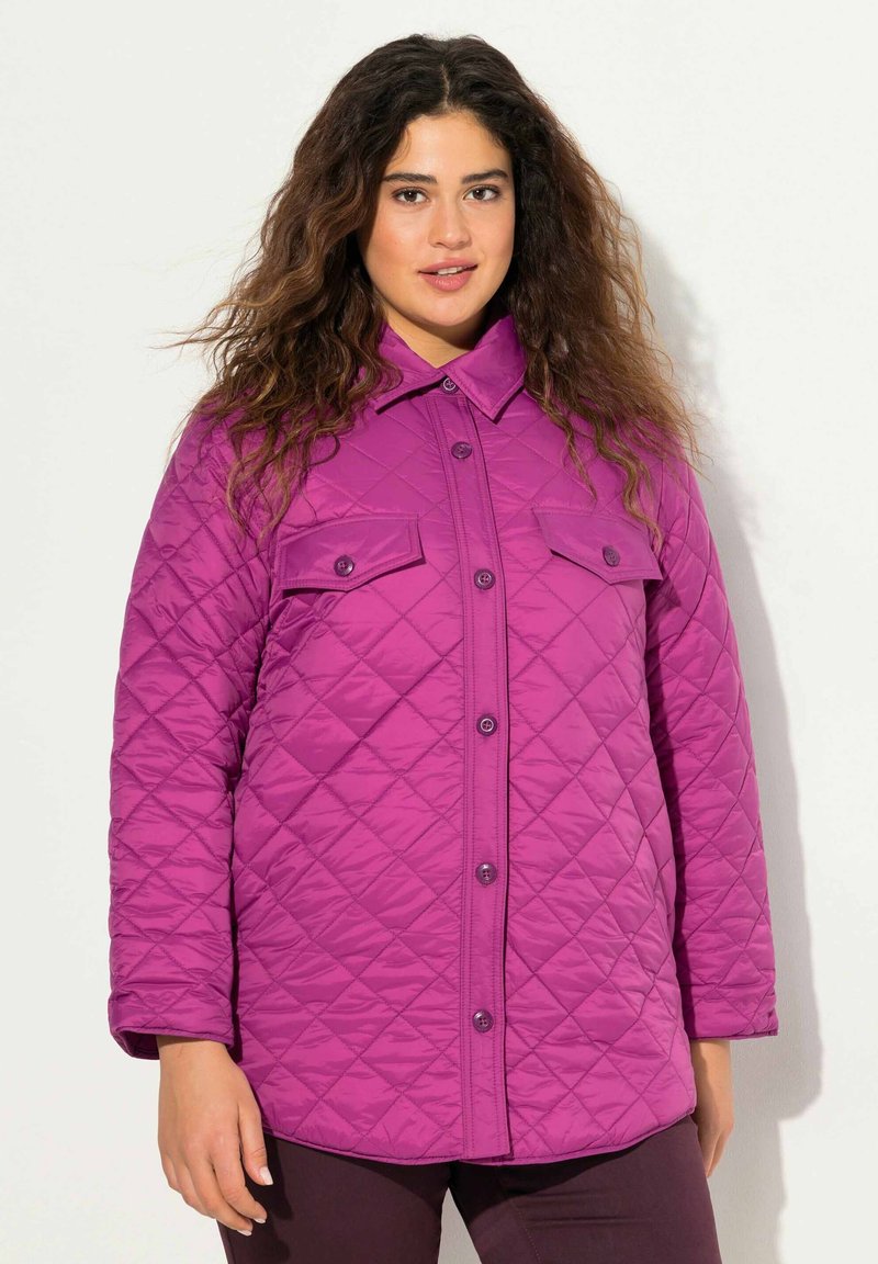 Quiltad lila jacka med knäppning fram, två bröstfickor och krage. Tyget har en slät struktur och ett diamantmönster.