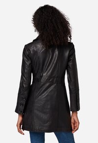 Zwart leren jasje met eenTailored ontwerp, lange mouwen, knoopdetails op de manchetten en een aansluitende tailleband. Gladde textuur en middellange snit.