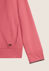 Sweatshirt rose en tissu doux, avec une poche latérale, un ourlet arrondi et des accents en imprimé léopard aux poignets. Détail logo doré.
